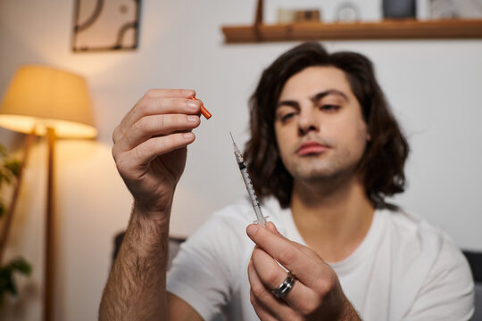 A young man demonstrates his daily health management while preparing his insulin at home.