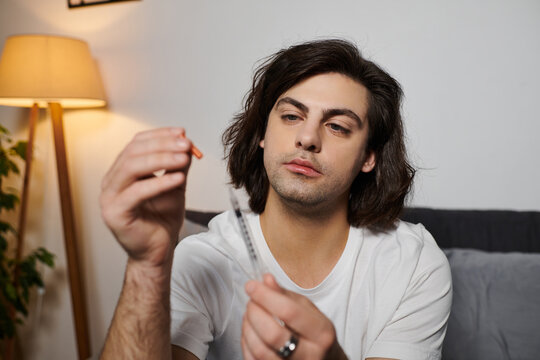 A young man with diabetes carefully measures insulin at home, showcasing his lifestyle choices.
