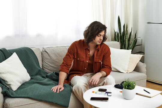Young man monitors his blood sugar levels while relaxing in a stylish living room.