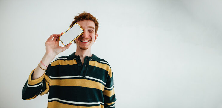 Young man portrait with smartphone in studio for mobile technology and social media concept
