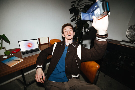 Candid vlogger uses camcorder for user generated content at desk