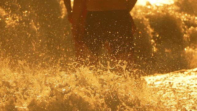 Ocean waves golden hour, two people standing in beautiful sea surf at sunrise or sunset, tranquil beach scene