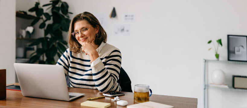 Middle-aged woman working remotely in cozy home office setting