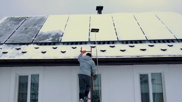 A man clears snow from solar panels. Selective focus.