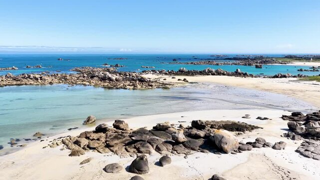 Eine beeindruckende Luftansicht vom Plage de Boutrouilles, bei der sanfte, wei&szlig;e Wellenmuster auf den hellen Sandstrand und die charakteristischen, dunklen Felsformationen treffen.