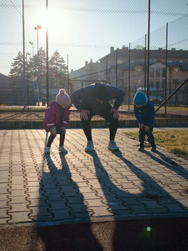 Father Stretching With Two Children Outdoors In Morning Light On Neighborhood Court