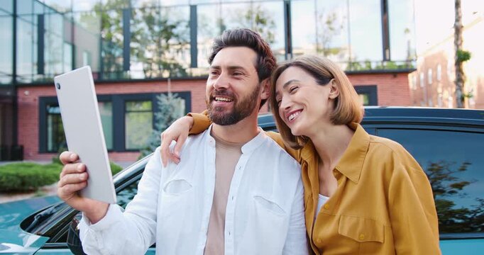 Portrait of joyful man and woman making video call on tablet outside, greeting friends with hand wave