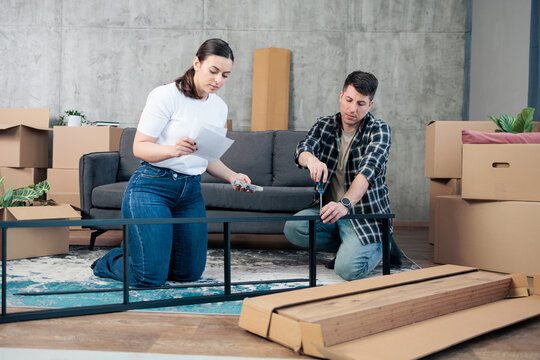 Couple assembling flat-pack furniture at home after moving