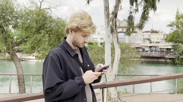 Lifestyle portrait of young man using a smartphone outdoors