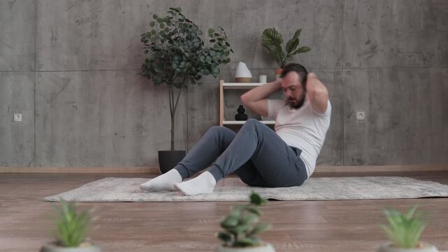 Young adult male performing abdominal crunches at home