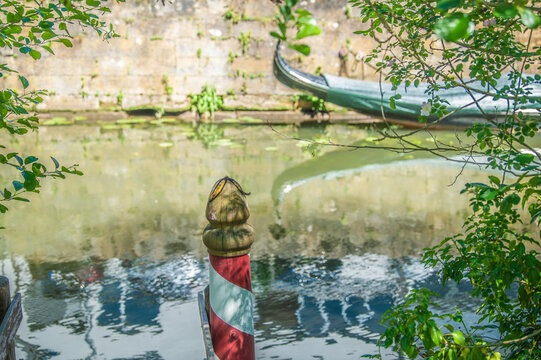 Selektiver Fokus auf rot-wei&szlig;en Anlegepfahl vor unscharfer Gondel und Sandsteinmauer am Ludwig-Donau-Main-Kanal am Flusspfad in Bamberg.