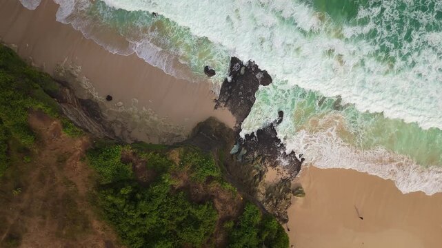 Cinematic aerial footage of an exotic beach paradise. People relaxing near ocean surf, sun umbrellas, and beachside infrastructure