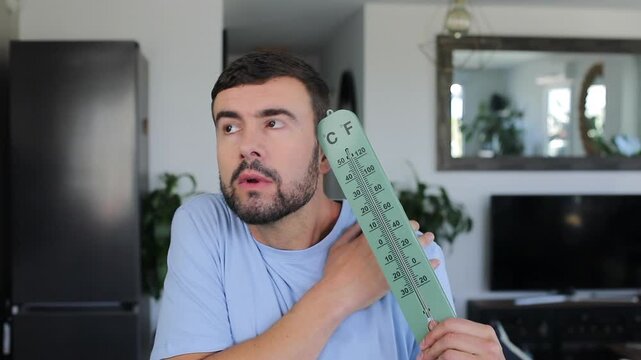 Man holding a large thermometer feeling cold