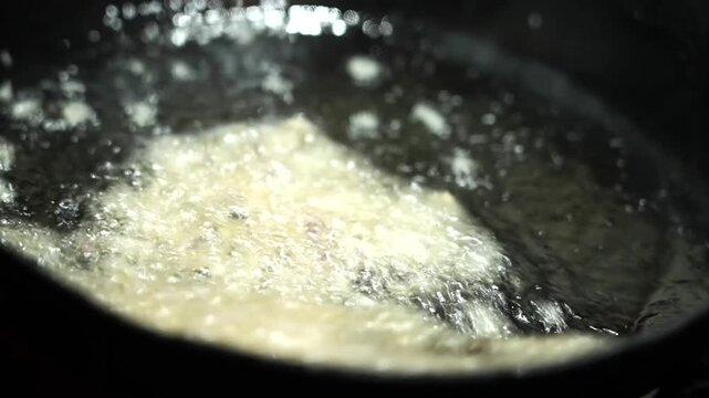 Close up shot of jalebis frying in hot oil during traditional Indian sweet preparation.