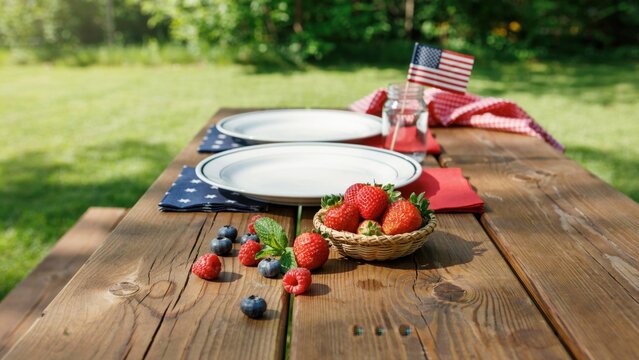 Picnic table features fresh strawberries and blueberries arranged for a summer celebration in an outdoor garden setting.