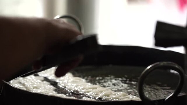 Close up shot of jalebis frying in hot oil during traditional Indian sweet preparation.