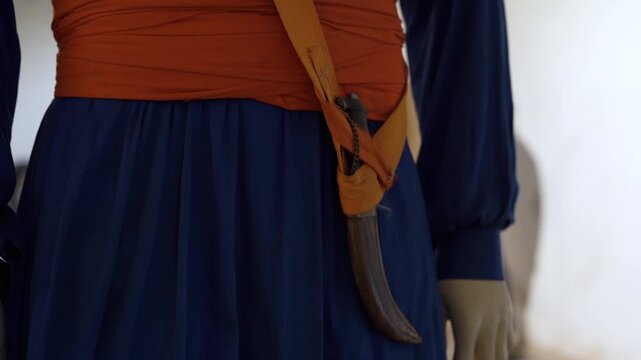 Close up of ceremonial Kripan and traditional attire of Nihang warrior in heritage museum setting.