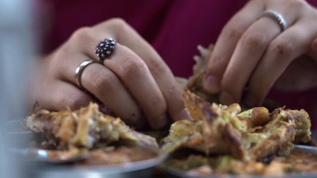 Human hand breaking soft flatbread during dining experience in India.
