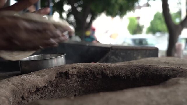 Traditional roti being prepared inside tandoor at roadside dhaba in India.