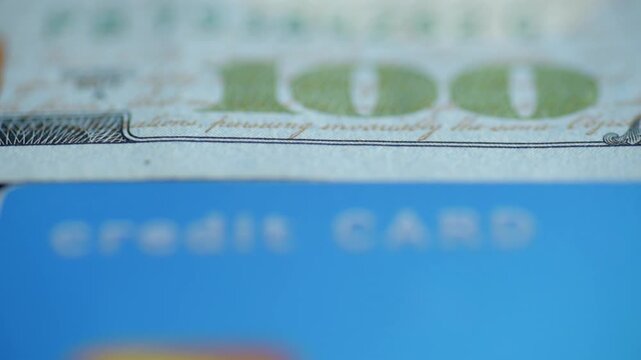 Closeup blue credit card with hundred dollar bill edge, shallow depth, chip blurred, textured plastic surface, subdued studio lighting, minimalist finance concept, purchase