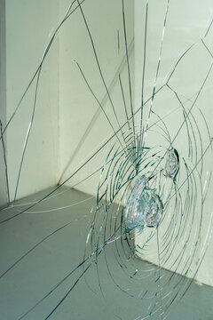 Side view of cracked storefront glass with broken impact pattern and urban vandalism concept
