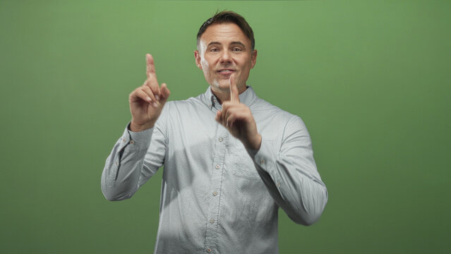 Man shadowboxing with clenched fists in green studio, throwing measured punches; training determination.