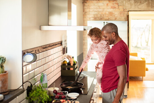 Father and daughter cooking breakfast together in home kitchen