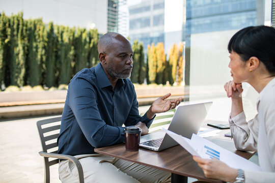 Business colleagues discussing report at outdoor cafe