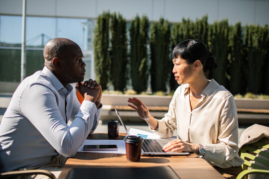 Two colleagues discussing work at an outdoor office patio