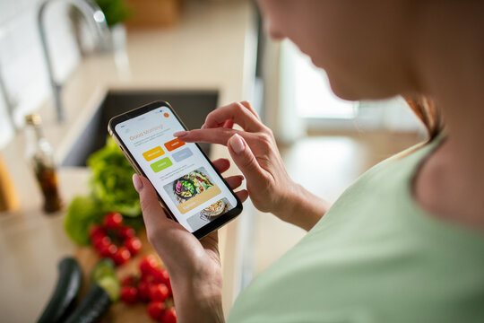 Woman using meal planning app in home kitchen