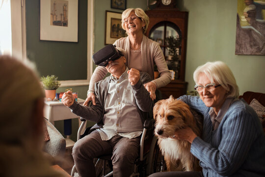 Senior man in wheelchair using vr with friends at home