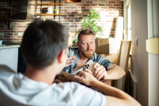 Two men discussing smartphone at home