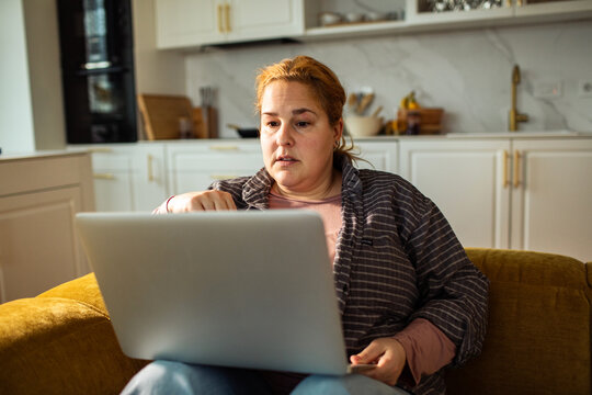 Focused woman working on laptop in cozy home kitchen