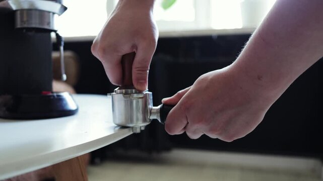 Barista tamping coffee grounds in portafilter for espresso preparation