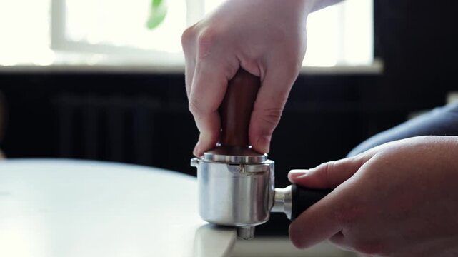 Barista tamping coffee grounds in portafilter for espresso preparation