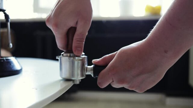 Barista tamping coffee grounds in portafilter for espresso preparation