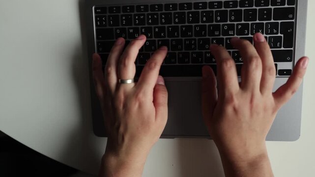 Close-up of hands typing on a laptop keyboard, showing fingers pressing keys