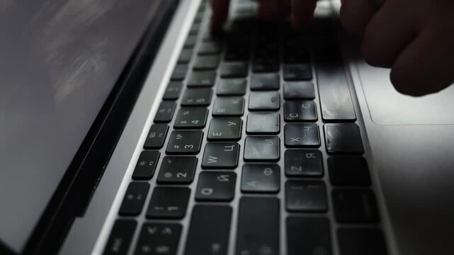 Close-up of hands typing on a laptop keyboard with a ring on one finger