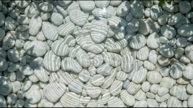 Droplet falling into clear water creating ripples over white pebbles. Zen stone background with liquid motion. Natural ripple pattern for relaxation and meditation.