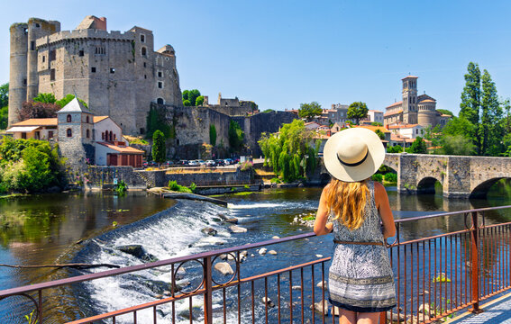 Woman traveler wearing straw hat admiring medieval castle and river in Clisson France
