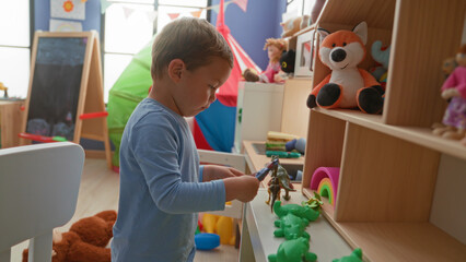 Fototapeta premium Boy places a toy dinosaur on a low shelf in a playroom inside a building, surrounded by plush fox, rainbow stacker and green frog toys; quiet concentration.