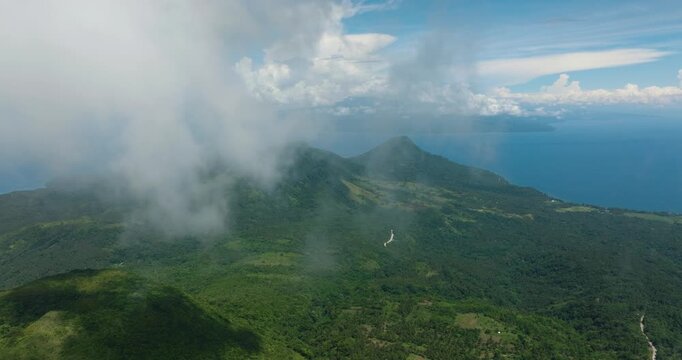 Mountains covered rainforest, trees and blue sky with clouds. Camiguin Island. Philippines.