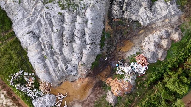 Aerial view reveals a quarried landscape. Mud flows through cracked, exposed rock faces