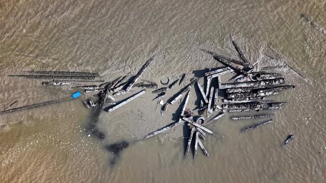 Aerial showing scattered wooden debris and miscellaneous objects in a muddy shallow river environment