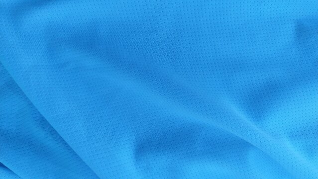 Soft blue football wear fabric texture background in detailed close up. Sports clothing textile material showing smooth pattern and fabric detail.