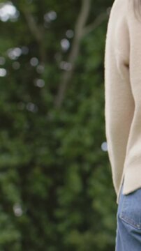 Vertical video: Holding hands, beige sweater walking in park for holiday, with watch and Santa hat