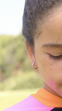 Vertical video: Cam revealing girl opening eye, reacting in park, pink top, silver hoop, copy space