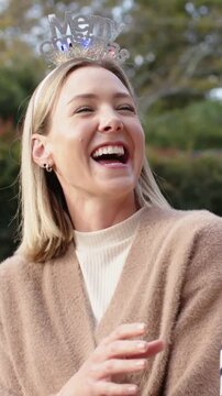 Vertical video: Laughing woman turning right after offcamera cue in garden wearing Merry headband