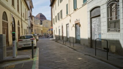 Fototapeta premium Narrow historic lane with defocused buildings and parked cars, soft bokeh street; background backdrop copyspace calm.