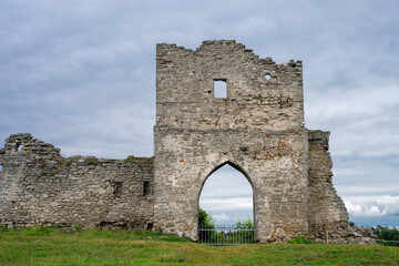the dramatic, weathered stone ruins of an ancient castle gatehouse, featuring a prominent pointed archway and crumbling walls in Kremenets, Ukraine © Andrey